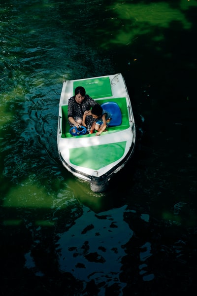 白天，穿着黑白衣服的女人坐在水上的蓝白相间的船上